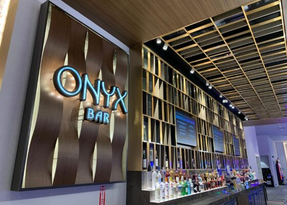 Onyx Bar dimensional wood-wave backdrop echoing the architectural ceiling feature at Choctaw Casino & Resort